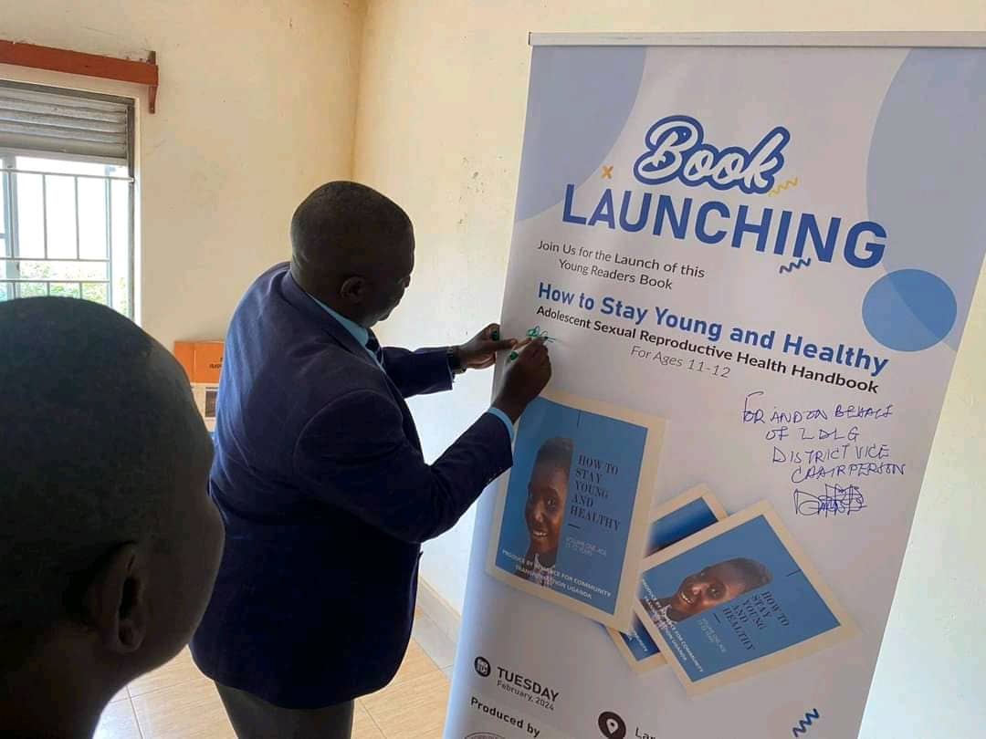 A local government official signing a banner at the launch of the ACT Uganda adolescent SRHR handbook