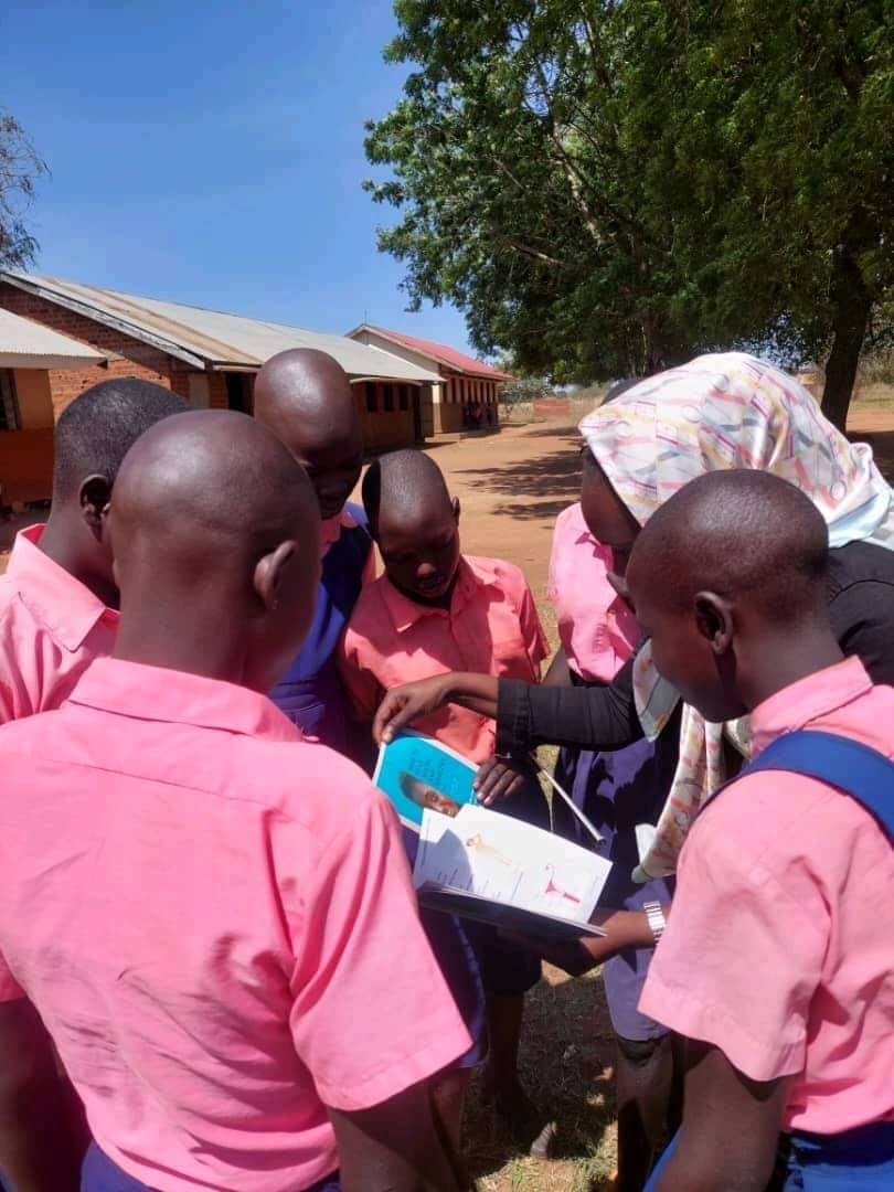 A facilitator reviewing the SRHR handbook together with a small group of students